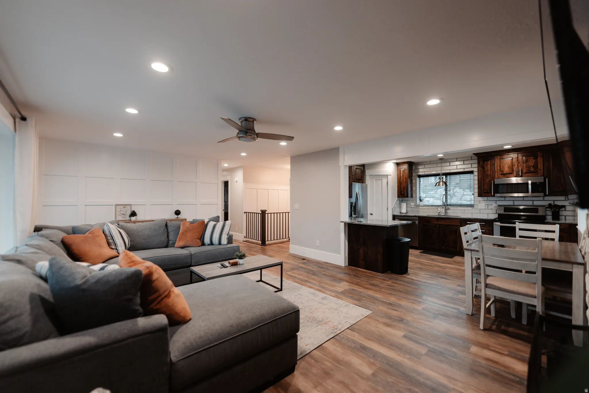 Open-concept living and kitchen area featuring recessed ceiling lighting, ceiling fan, wood-finish flooring throughout, and stainless steel appliances