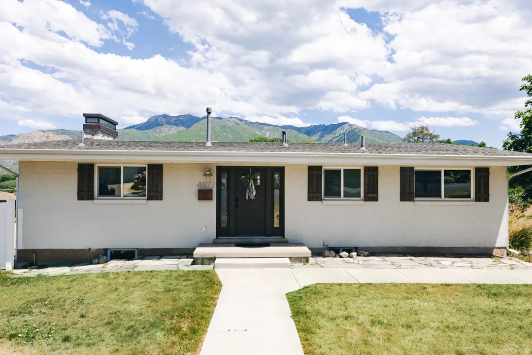 Modern ranch-style residence featuring a clean, geometric facade with horizontal bands of black-framed windows, a centered brown entry door with sidelights, and a flat roofline