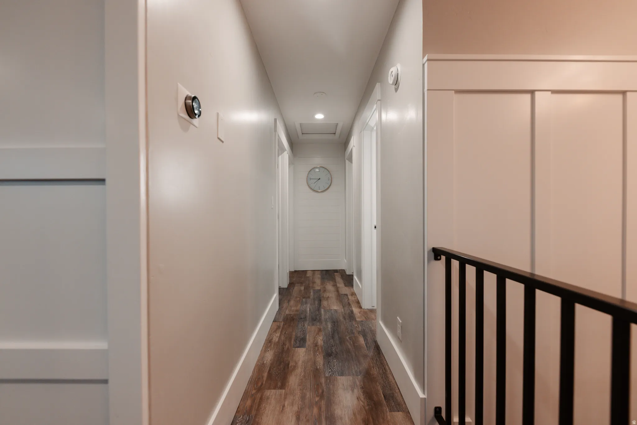 Bright hallway featuring recessed lighting, white painted walls, wood-finish flooring, and multiple closet storage options with white panel doors