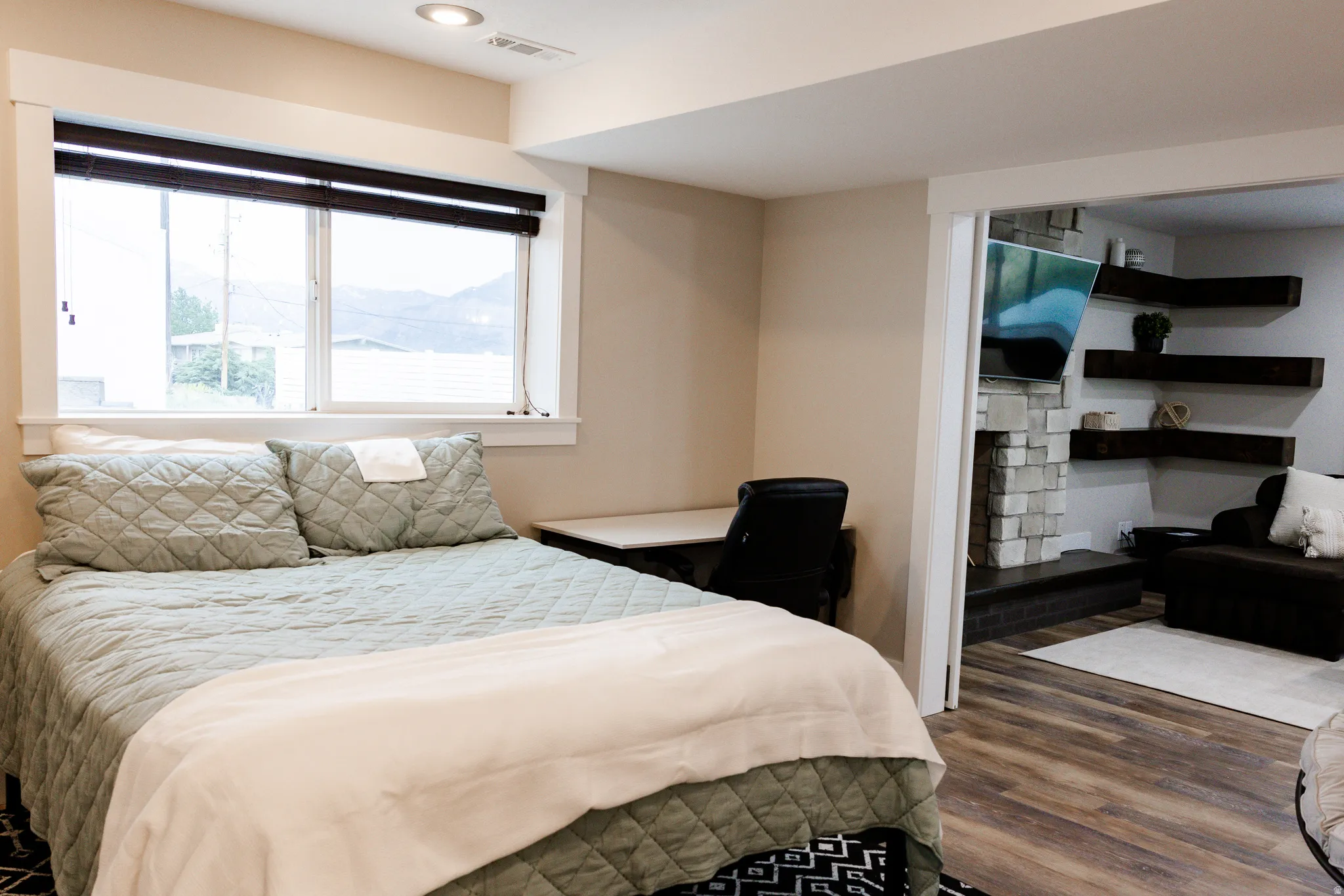 Bright basement bedroom with expansive windows featuring water views, neutral color palette, and wood-finish flooring