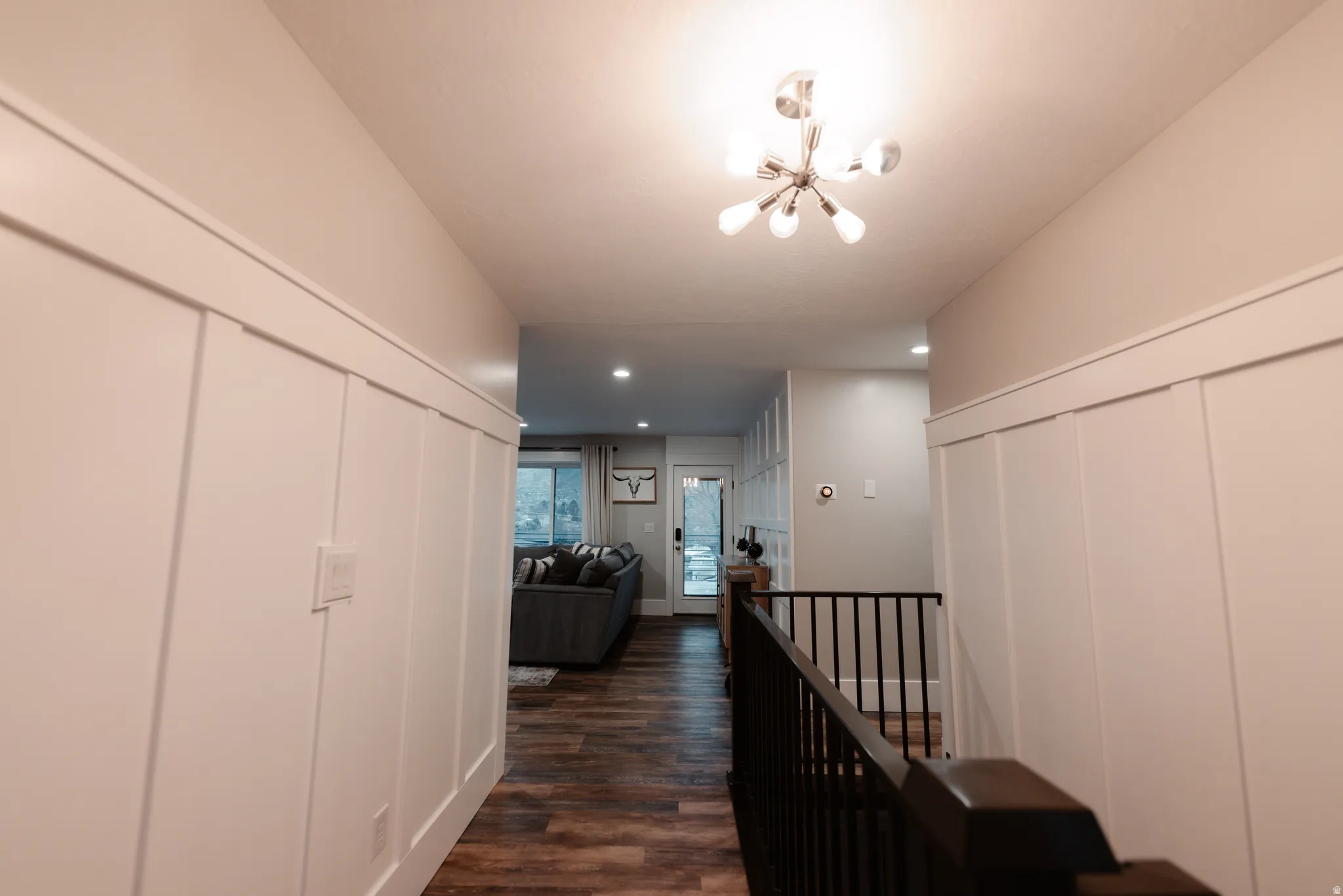 Hallway featuring wainscoting, wood-finish flooring, and a contemporary ceiling light fixture