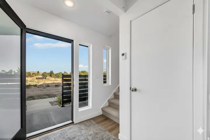 Recessed lighting, wood-finish flooring, full-light entry door, side-light window, and carpeted staircase