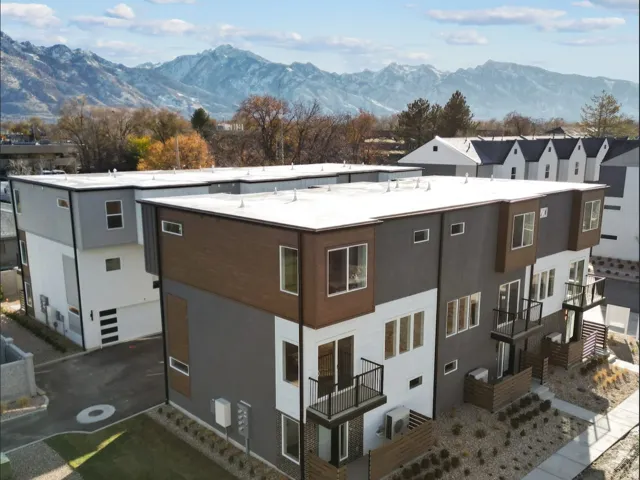 Modern multi-level townhome featuring a flat roofline, private balconies, and a contemporary facade with varied siding materials