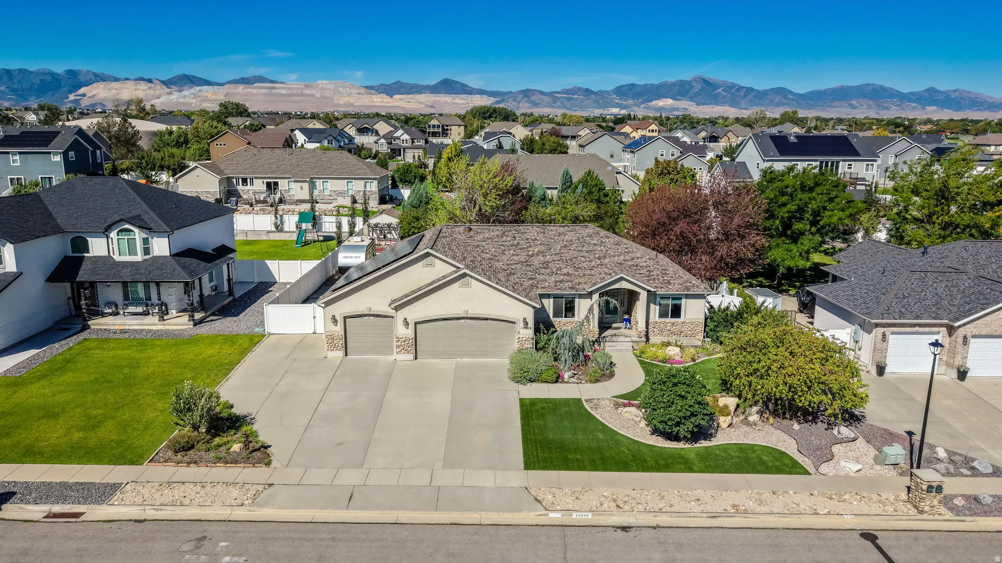 Ranch-style residence featuring a two-car garage, stone and stucco exterior, and a landscaped front yard with a concrete driveway