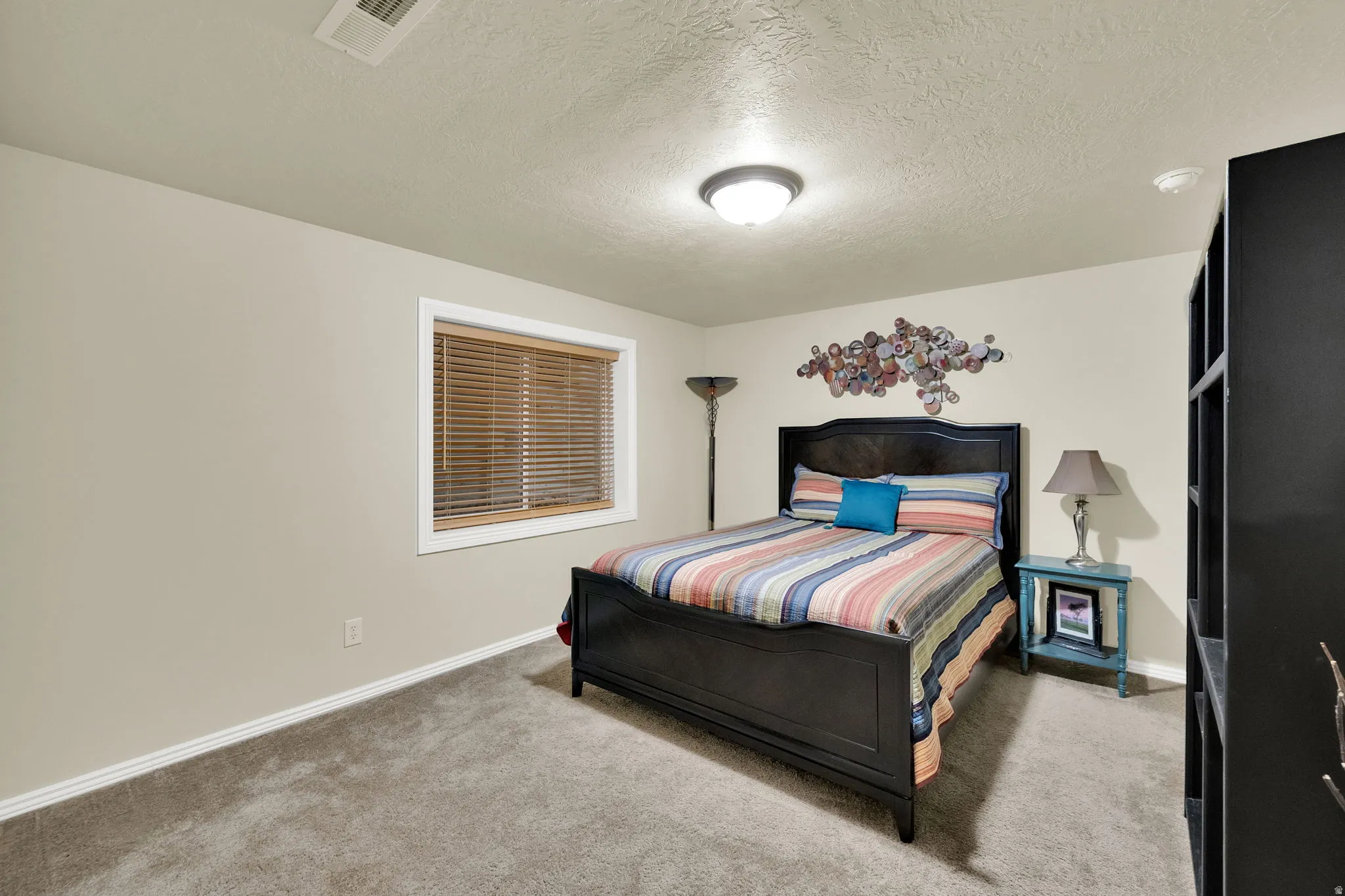 Neutral wall tones, window with wood-finish blinds, plush carpeting, and built-in shelving