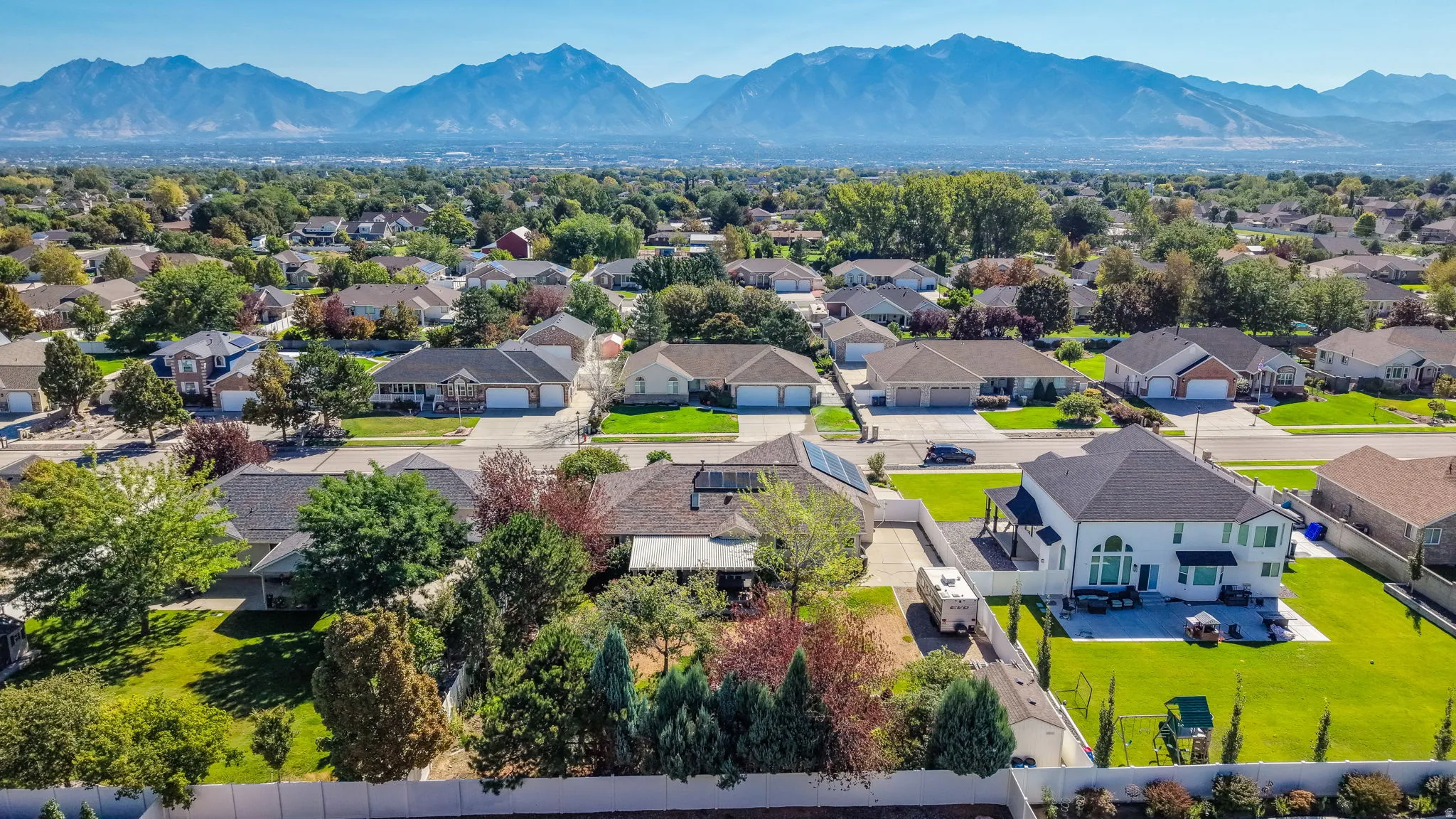 Expansive neighborhood setting with mature trees and mountain backdrop