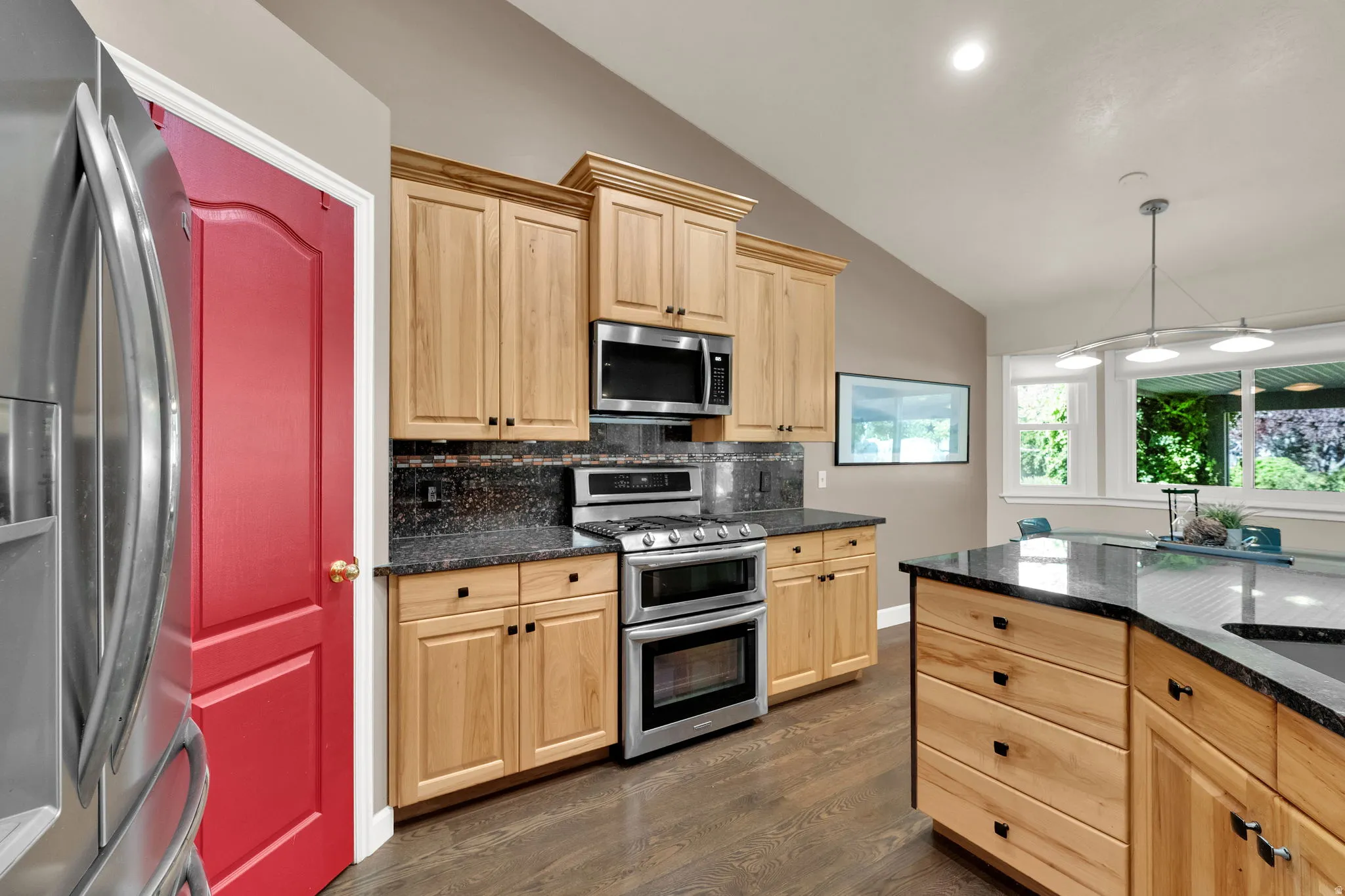Wood-finish flooring, stainless steel appliances, light wood cabinetry, dark granite countertops, and recessed lighting