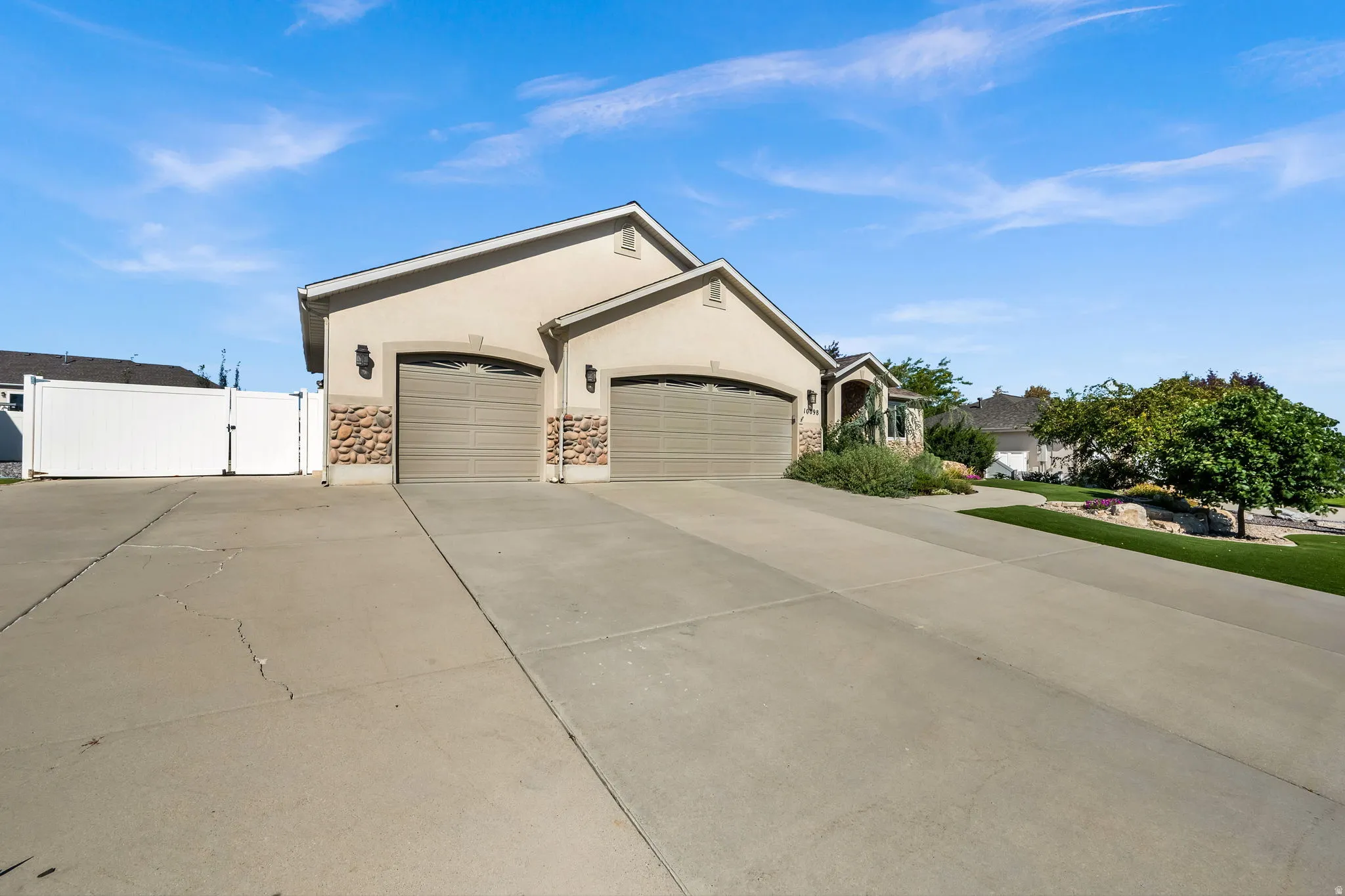 Spacious driveway with dual attached garages featuring paneled doors and stone accents