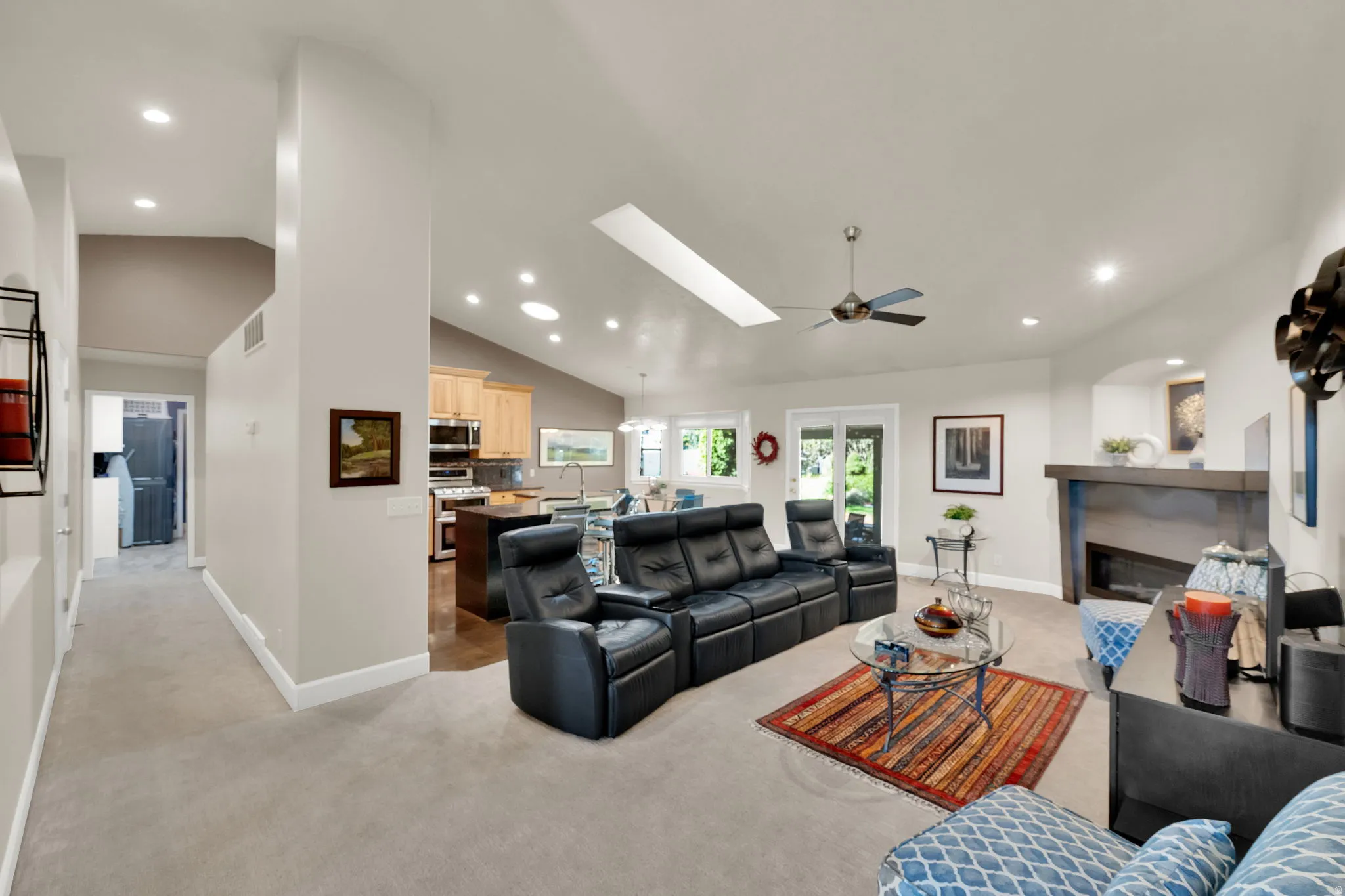 Vaulted ceiling with recessed lighting and skylight, ceiling fan, built-in fireplace, and wood-finish flooring in the background