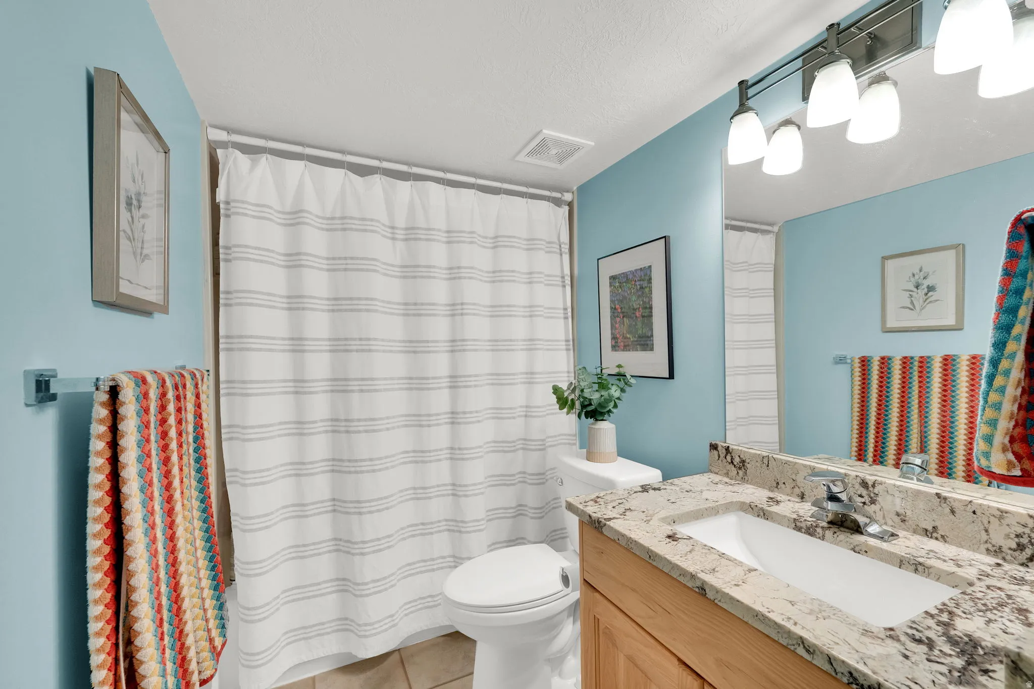 Bathroom featuring a vanity with a stone-finish countertop, undermount sink, and wood-finish cabinetry