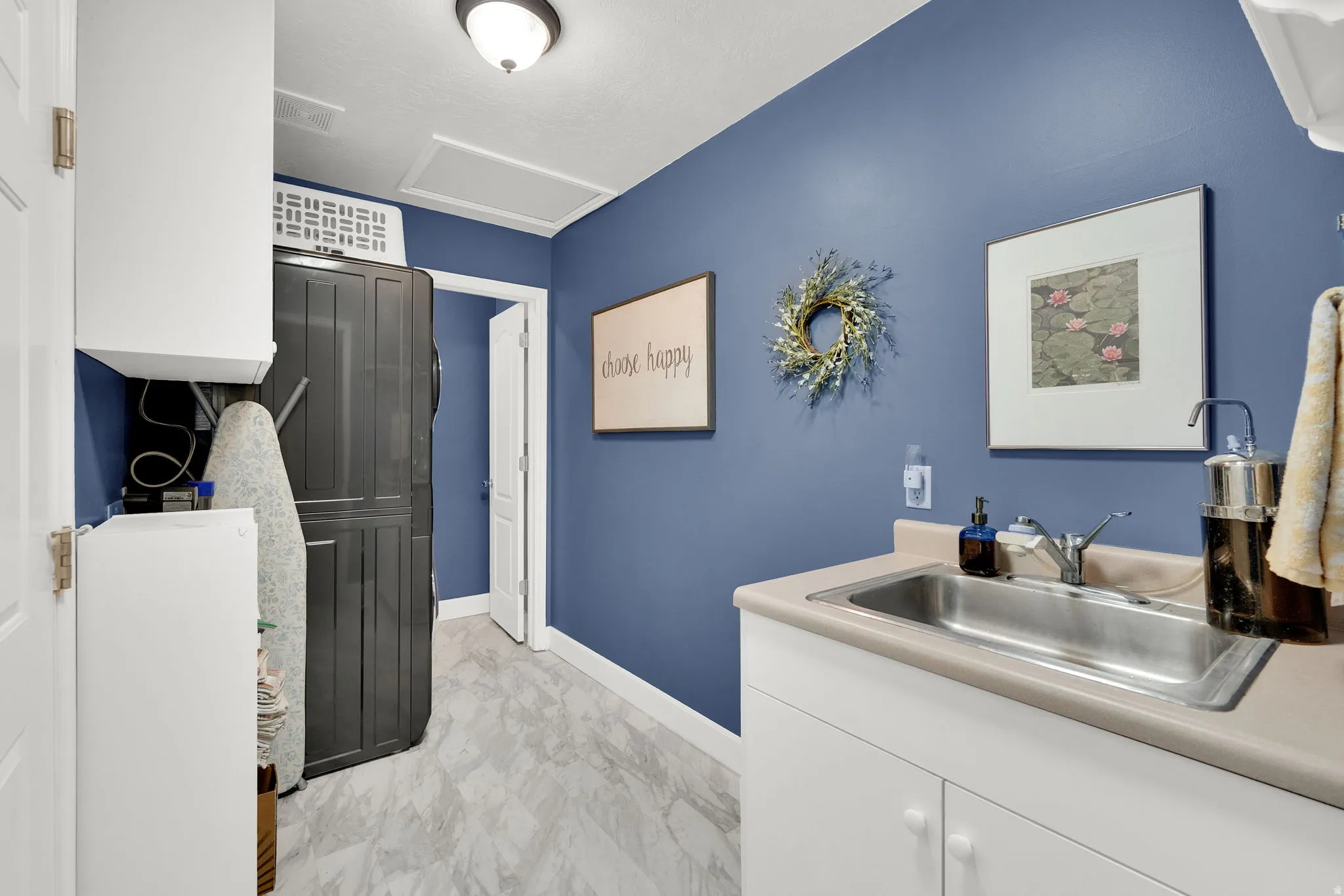 Laundry room featuring a utility sink, light countertops, white cabinetry, and a light fixture