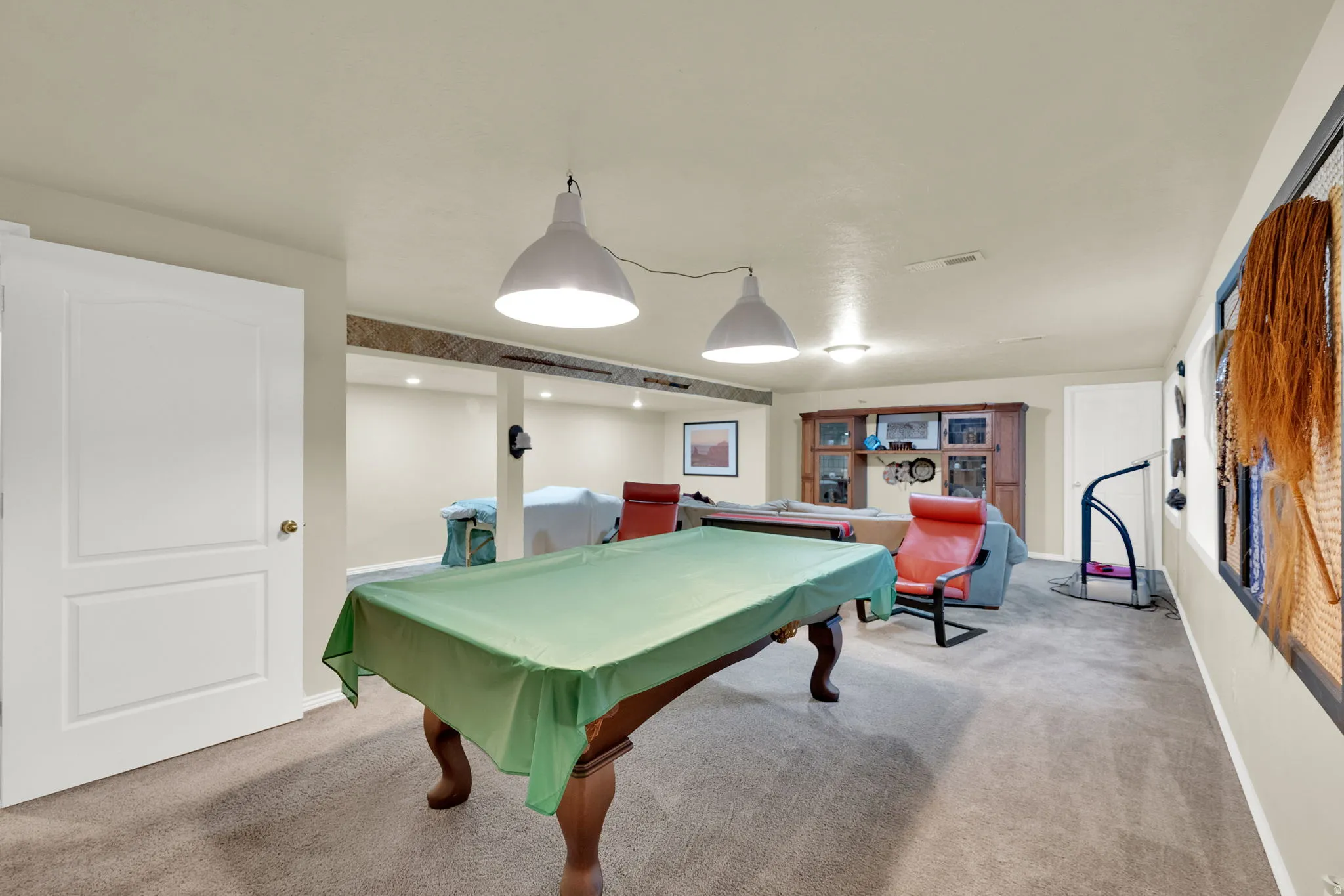 Carpeted recreation area with recessed lighting, exposed ceiling beam, and built-in cabinetry