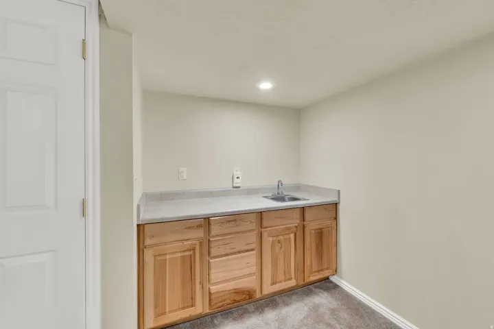 Built-in cabinetry with a light-toned countertop, stainless steel sink, and a single-handle faucet