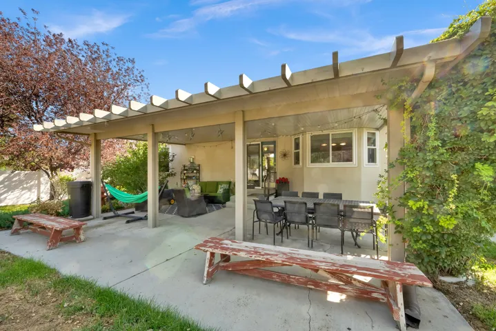 Expansive concrete patio with a wood pergola, overlooking a landscaped yard