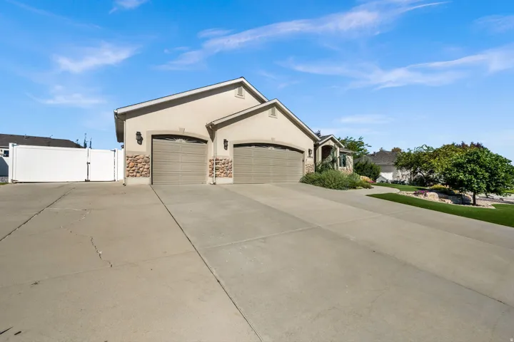 Spacious driveway with dual attached garages featuring paneled doors and stone accents