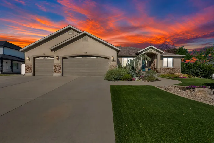Stucco exterior with stone accents, concrete driveway, two-car garage, mature landscaping, and an inviting front walkway