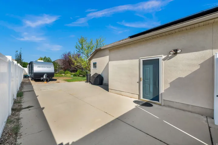 Expansive concrete driveway with ample parking space, mature landscaping, and direct access to the residence