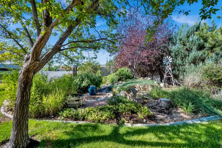 Lush landscaping featuring mature trees, diverse plantings, and a decorative windmill