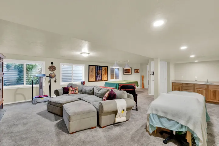 Spacious recreation room featuring plush carpeting, recessed lighting throughout, and large windows with plantation shutters