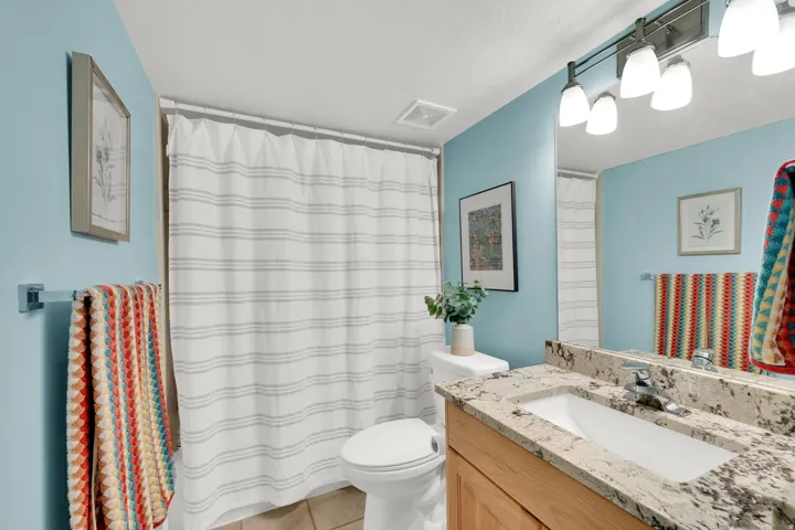 Bathroom featuring a vanity with a stone-finish countertop, undermount sink, and wood-finish cabinetry