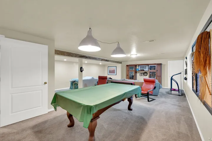 Carpeted recreation area with recessed lighting, exposed ceiling beam, and built-in cabinetry