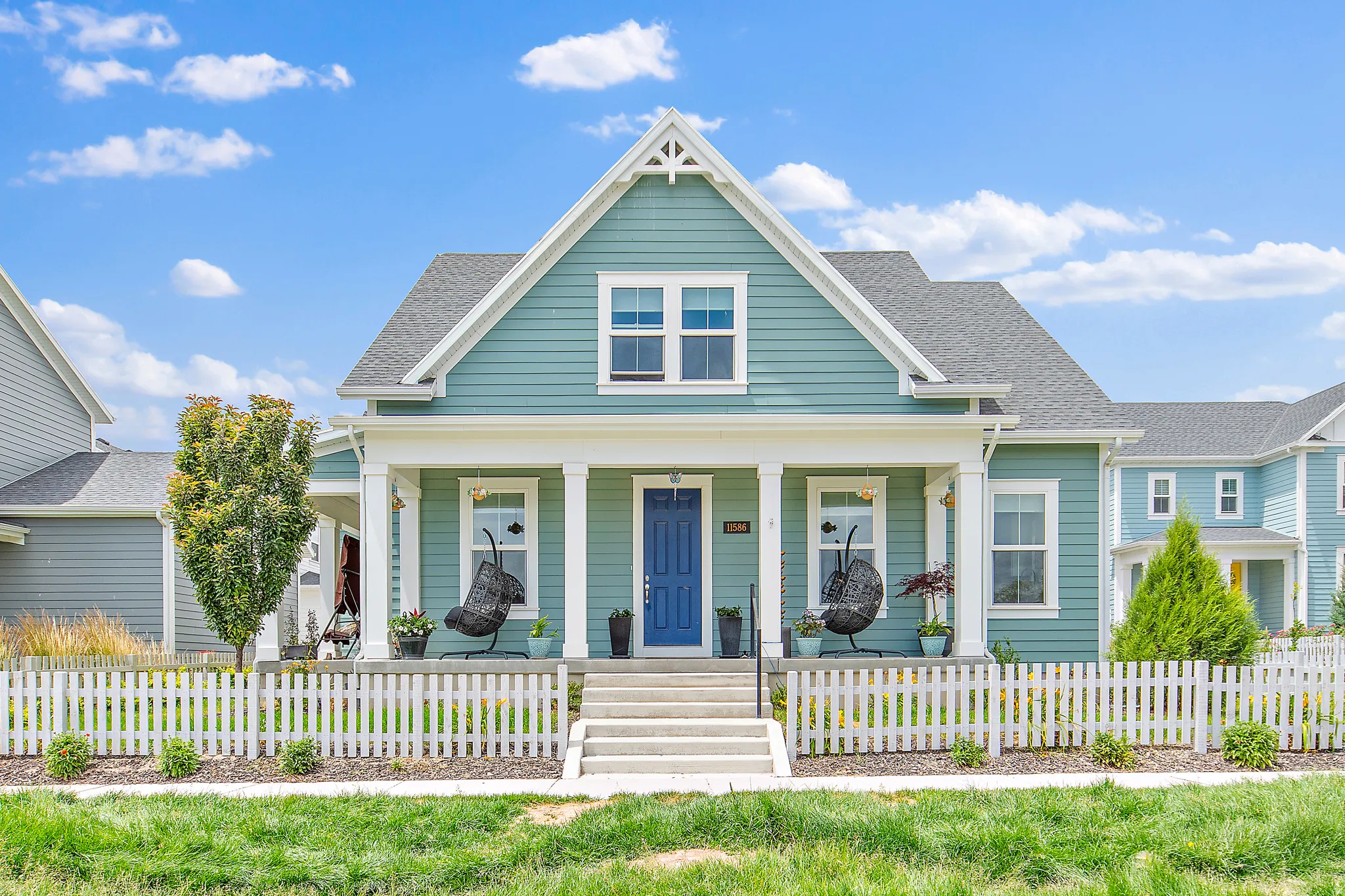 Charming farmhouse featuring a light blue board-and-batten exterior with contrasting white trim and gable detailing