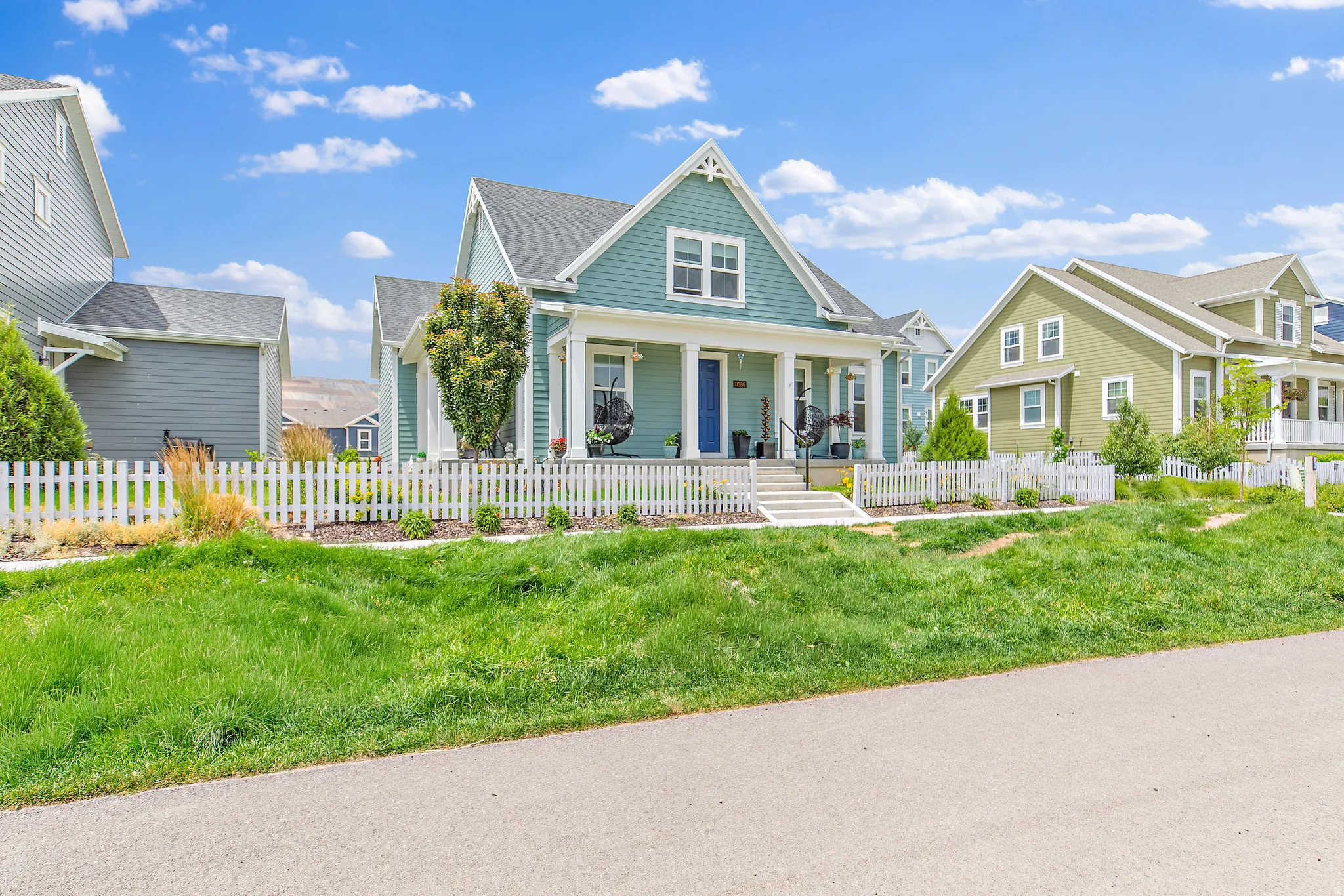 Charming farmhouse-style residence featuring a gabled roof with multiple peaks, light blue exterior siding, and white trim accents