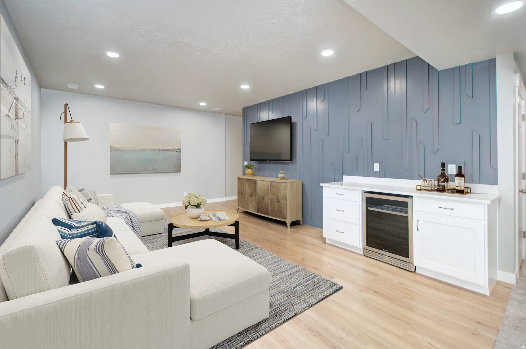 Recessed ceiling lighting, wood-finish flooring, accent wall paneling, built-in cabinetry with white countertop, and integrated beverage cooler and surround sound