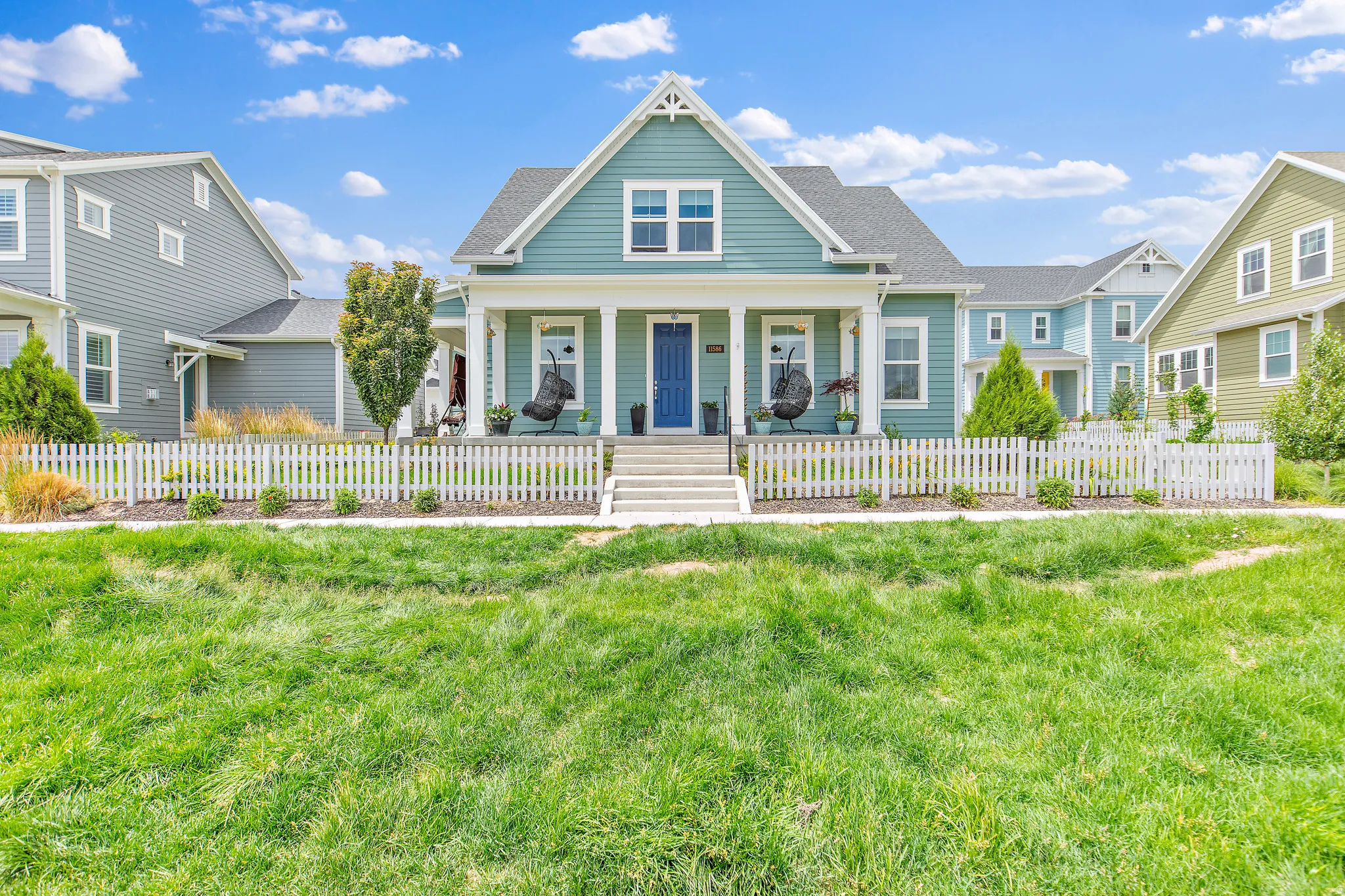 Charming farmhouse-style residence featuring a gabled roofline with architectural detailing, sage-green exterior siding, and white trim