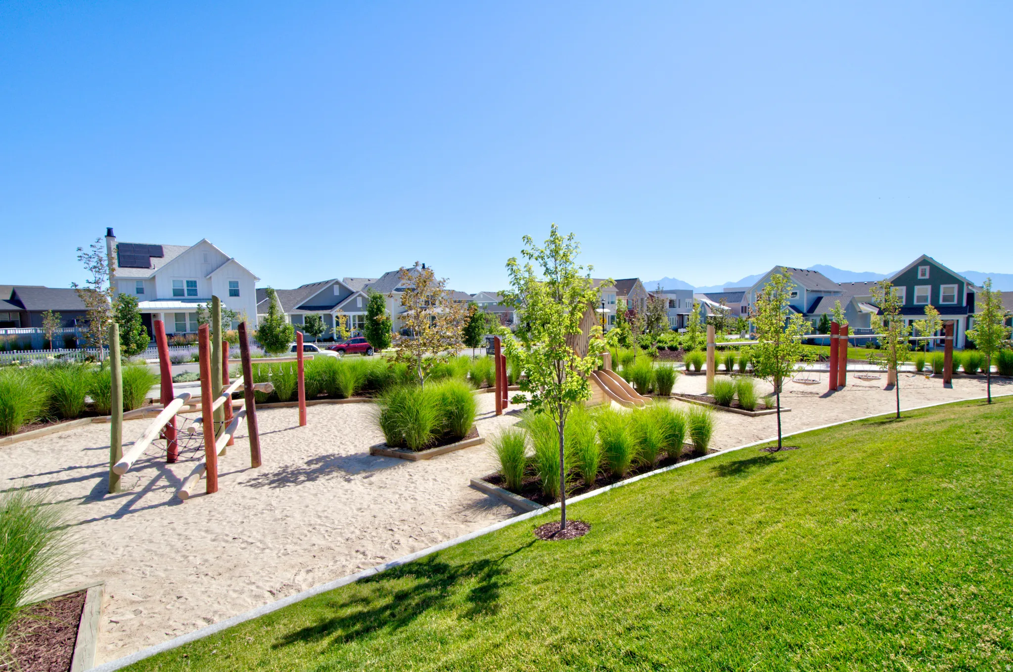 Expansive outdoor recreational space featuring a sand play area, climbing structures, and a slide