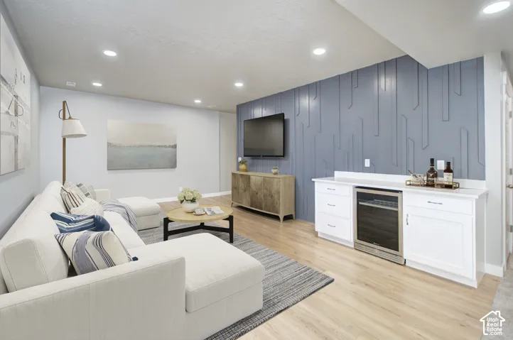 Recessed ceiling lighting, wood-finish flooring, accent wall paneling, built-in cabinetry with white countertop, and integrated beverage cooler and surround sound