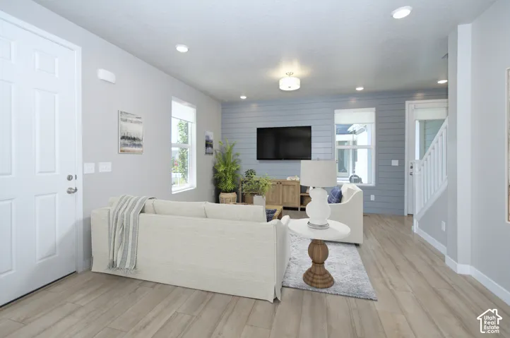 Open-concept living rear featuring wood-finish flooring, recessed lighting, white trim, and a shiplap accent wall
