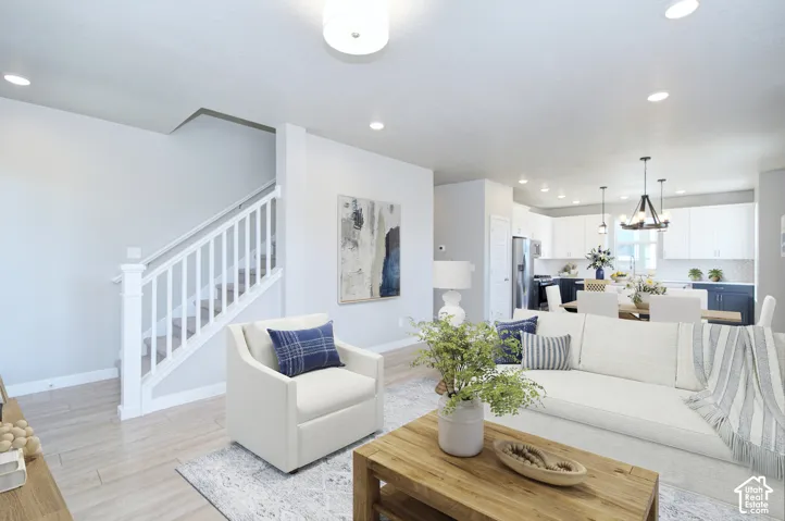 Recessed lighting, wood-finish flooring, white staircase with railing, white shaker kitchen cabinetry, and pendant lighting