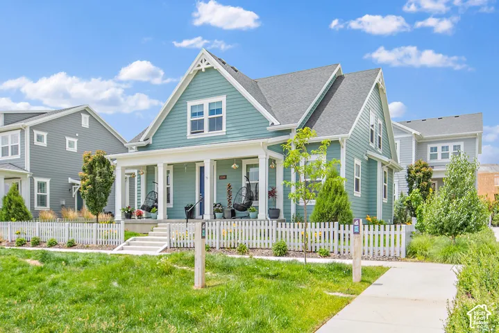 Charming farmhouse-style home featuring a light blue-green exterior with white trim, gabled roofline, and a full-width front porch with white picket railing