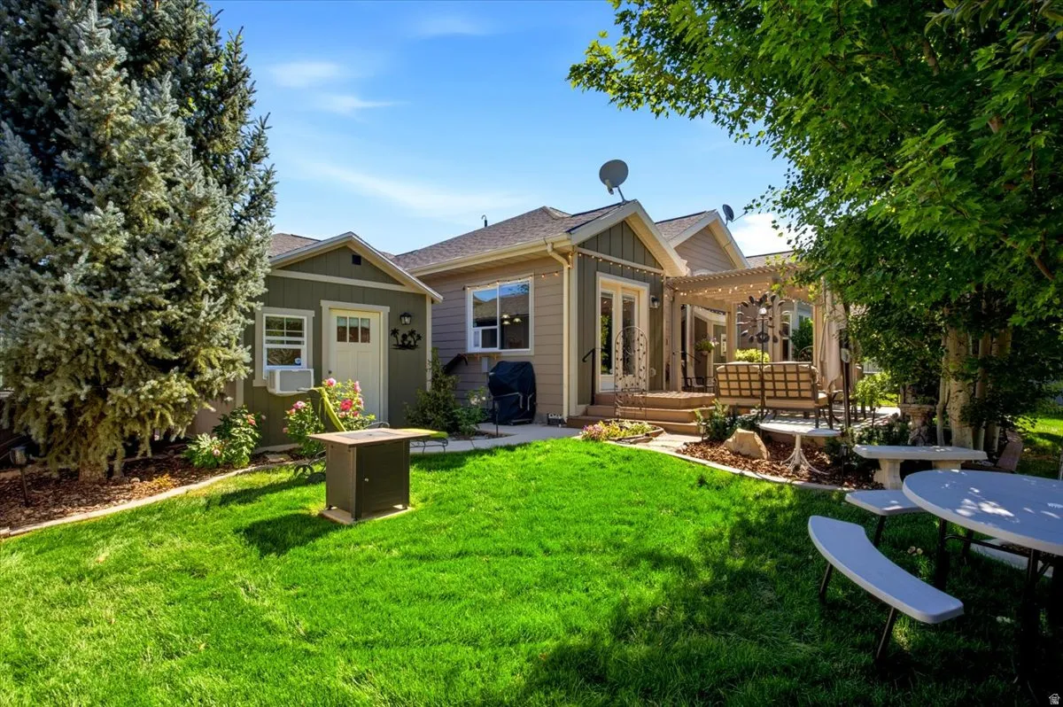 Large custom deck with a pergola cover, patio lighting, mature trees, an electric standing waterfall, vegetable garden, and finished shed with heat and AC.