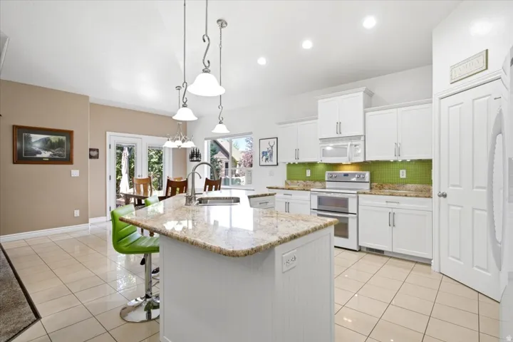 The upgraded kitchen features white shaker skyline cabinetry, granite countertops, a tile backsplash, under-cabinet lighting, and soft-close doors and drawers.