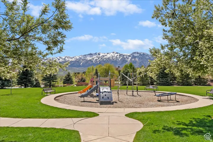 Recreational park area with playground equipment, surrounded by green lawns and mature trees