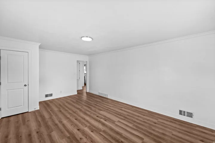 Wood-finish flooring, white walls, and a flush-mount ceiling light