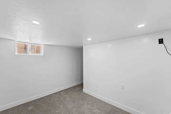 Plush carpet flooring, recessed ceiling lighting, a window, and white walls