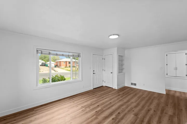 Wood-finish flooring, built-in shelving, white walls, flush-mount lighting, and dual-pane windows