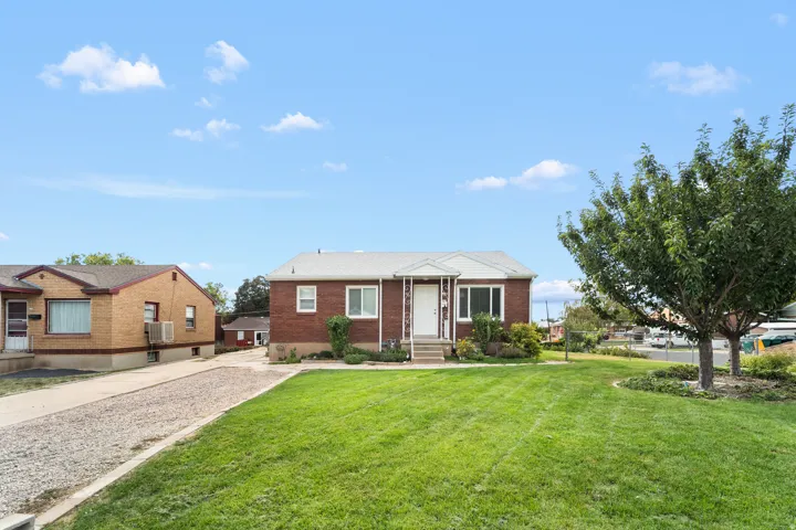 Brick exterior with white trim, front porch entry, and a gravel driveway