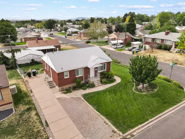 Red brick exterior with white trim, a gabled roof, a concrete driveway, and a front yard with mature landscaping