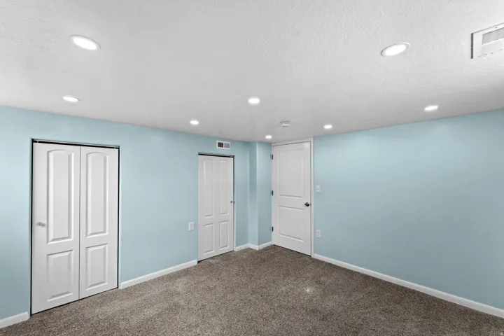 Spacious recreation room featuring soft blue walls, recessed ceiling lighting, and neutral carpet flooring