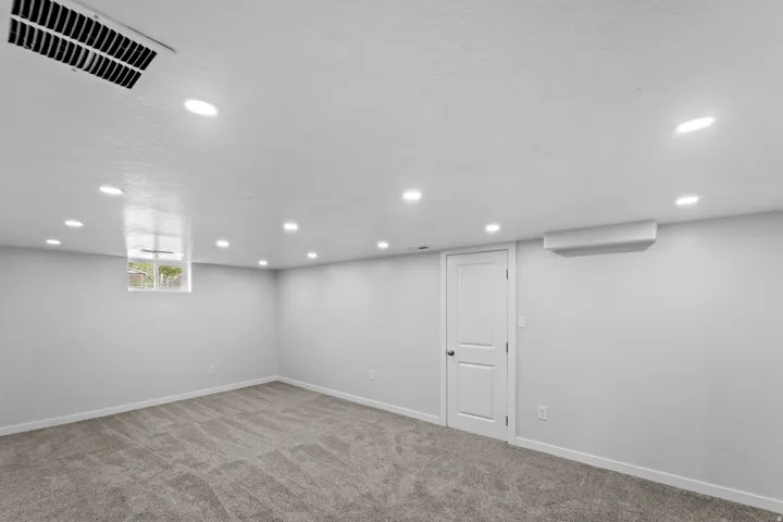 Recessed lighting, light gray carpeting, white walls, and a white interior door