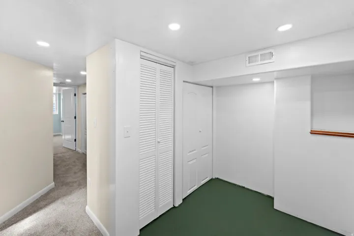 Recessed lighting, louvered bi-fold closet doors, carpeted hallway, wood-finish trim, and interior doors