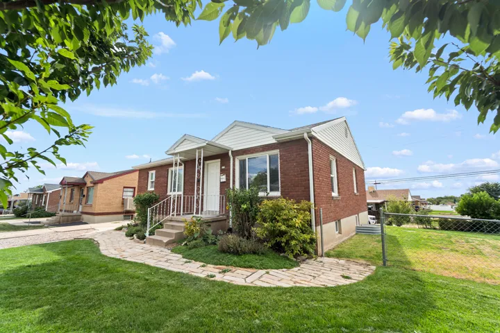 Red brick exterior with white trim, front porch with white railing, concrete steps, and a paver walkway