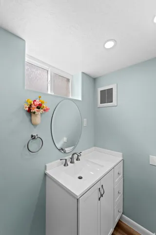 White vanity with a single basin sink, brushed nickel faucet, and integrated countertop