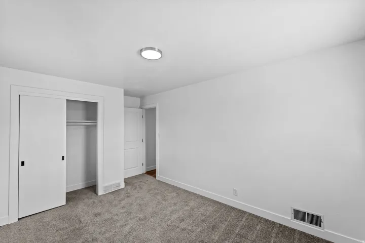 Wall-to-wall carpeting, white walls, and a flush-mount ceiling light