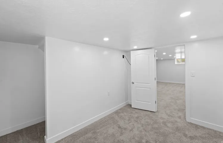 Recessed lighting, light gray carpeting, and a white two-panel interior door