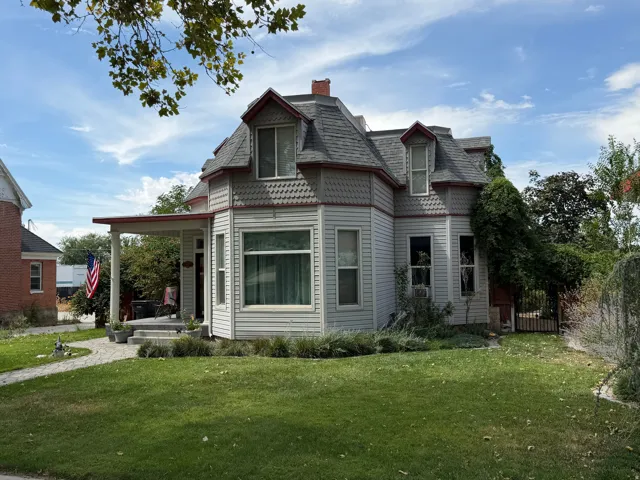 Victorian-style exterior with gray siding and red trim, featuring a covered porch